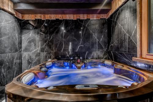 une baignoire dans une salle de bain avec du carrelage noir dans l'établissement Chalets ANNAPURNA Lodge GANGA & Lodge MACHA 5 étoiles, à Tignes