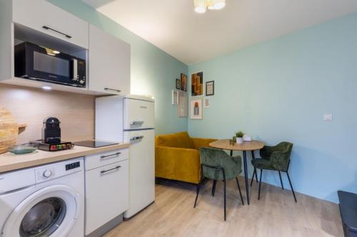 una cucina con lavatrice e tavolo di La Suite St-André - T2 Art Déco - Centre ville a Clermont-Ferrand