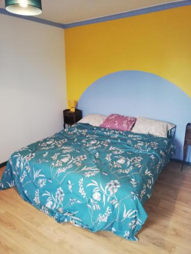 a bedroom with a bed with a blue comforter at maison des trois rivières in Trévières