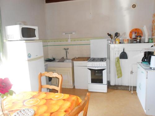 une cuisine avec des appareils électroménagers blancs et une table avec un four micro-ondes dans l'établissement chez Ernestine, à Pléguien