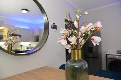 a vase with pink flowers on a table in front of a mirror at Eirini Elegant - Hermes Apartment in Midrand