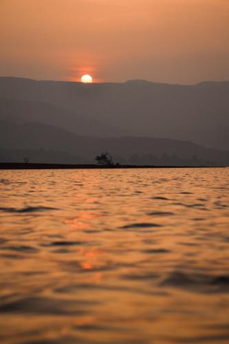 a sunset over a large body of water at Mysticstays Resort in Wai