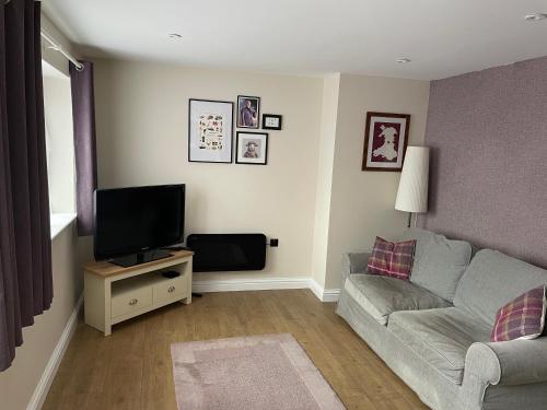 ein Wohnzimmer mit Sofa und Fernseher in der Unterkunft Blackberry Cottage in Cardiff