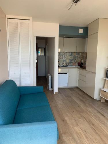 un salon avec un canapé bleu et une cuisine dans l'établissement Studio Tahiti beach face à la mer, à Frontignan
