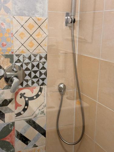 a shower with a hose in a bathroom with tiles at Amical Hotel Hagen - Am Hauptbahnhof in Hagen