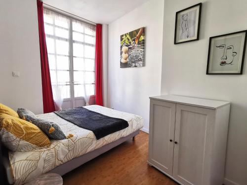 une chambre avec un lit et une fenêtre avec des rideaux rouges dans l'établissement Petit Vitet, à Dieppe