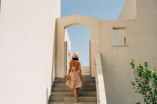 a woman walking up the stairs of a building at Makrikythera Luxury Suites - Private Pool or Hot Tub Suites in Dhiakofti