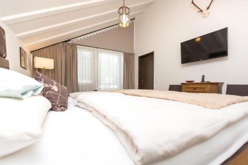 a bedroom with a bed and a flat screen tv at Hotel Alpenhof Postillion in Kochel