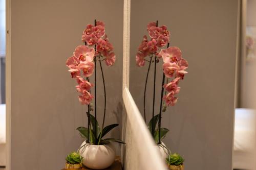 two vases with pink flowers inront of a mirror at Dolce Vita Spa & Terrace Suite by C&G in Florence