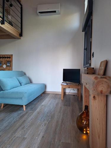 un salon avec un canapé bleu et une télévision dans l'établissement Lodge les ombelles, à Coutras