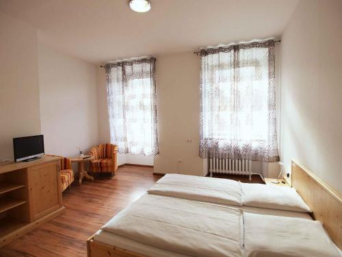 a bedroom with two beds and a desk and two windows at Hotel Klosterhof in St. Blasien