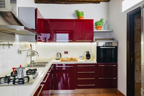 una cucina con mobili rossi e un lavandino di I Carrettieri - a few steps from the Cathedral a Palermo