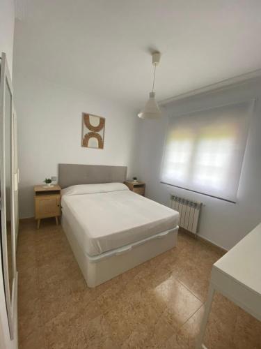 a white bedroom with a bed and a window at Chalet en Suances in Ongayo