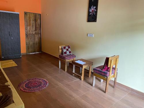 two chairs and a table in a room at hornbill homestay in Pendur
