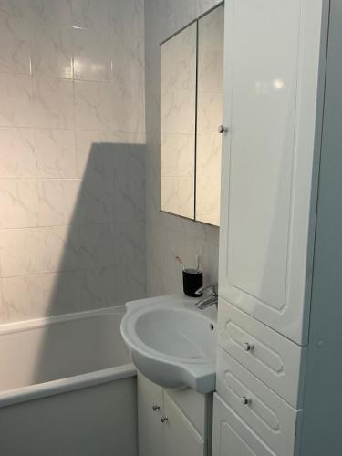 une salle de bain blanche avec un lavabo et une baignoire dans l'établissement Tout à pied, à Cabourg