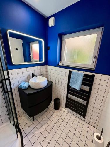 une salle de bain bleue avec un lavabo et un miroir dans l'établissement Nid douillet - Maison tout équipée, à Bordeaux