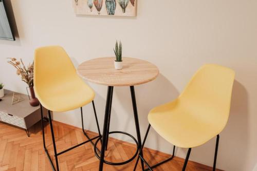 two yellow chairs and a table in a room at CityBeat Apartments, 400m from the square in Plzeň