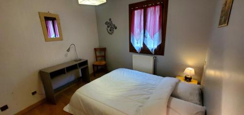 a bedroom with a bed and a desk and two windows at Le logis de l'Ajolaise in Vielle-Aure