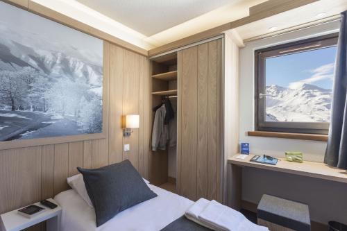 a bedroom with a bed and a window with snow at Hôtel Club mmv Les Arolles **** in Val Thorens