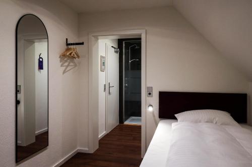 a bedroom with a white bed and a mirror at schlossmühle - lean luxury boutique hotel in Glottertal