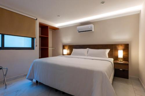 a bedroom with a large white bed and a window at Hotel 28 Cancun in Cancún