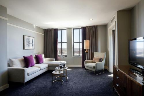 a living room with a couch and chairs and a tv at Ambassador Hotel Wichita, Autograph Collection in Wichita