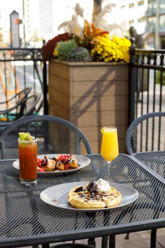 two plates of food on a table with drinks at Ambassador Hotel Wichita, Autograph Collection in Wichita