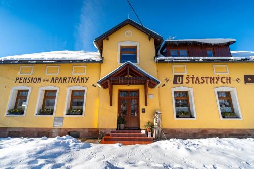 a yellow building with snow in front of it at Apartmány U Šťastných in Cerny Dul