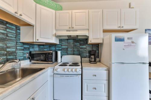 a kitchen with white cabinets and a sink and a refrigerator at Coastal Waters in New Smyrna Beach