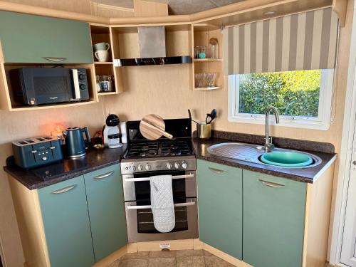 a small kitchen with a stove and a sink at Stylish Inviting 2 Bedroom Caravan with Sea View in East Mersea