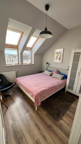 a bedroom with a bed with a pink comforter and two windows at Wodniak in Ostróda