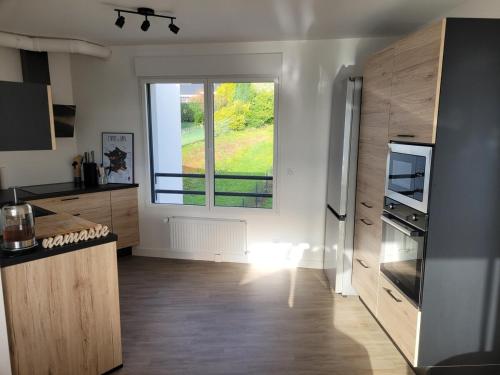 Il comprend une cuisine équipée d'un réfrigérateur et une grande fenêtre. dans l'établissement T2 récent, tout équipé et bel extérieur, à Quimper