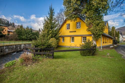 a yellow house with a fence in front of it at Penzion SATEK in Lipova Lazne