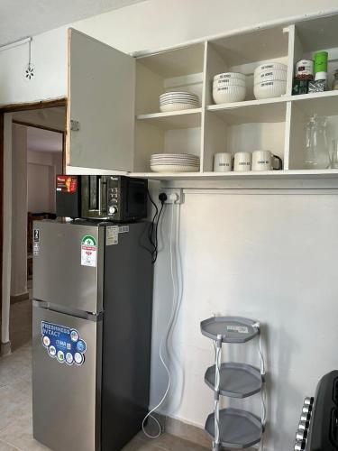 a kitchen with a refrigerator and a stool and shelves at Zoe Homes VIKAS Oak 1 bedroom 201 in Kericho