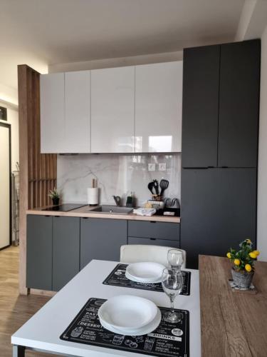 Una cocina con gabinetes blancos y platos blancos sobre una encimera. en Lemon Bliss Studio, en Skopje