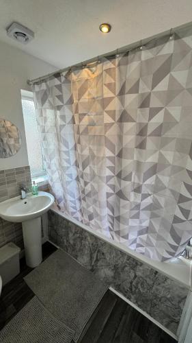 a bathroom with a shower curtain and a sink at Little Luxe shared house in Bristol