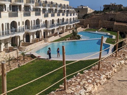two people standing next to a swimming pool next to a building at Hal Wardija Sunny Retreat in Qala