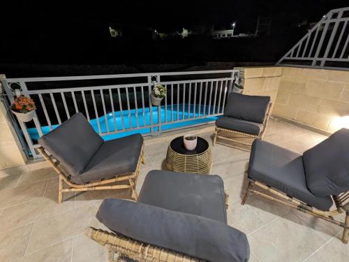 a patio with chairs and a swimming pool at night at Hal Wardija Sunny Retreat in Qala