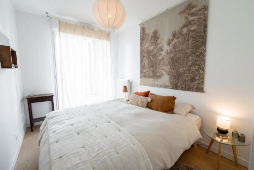 a white bedroom with a large bed and a window at Spacious bright contemporary apartment in Bordeaux
