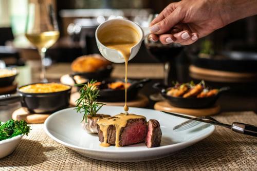 a person drizzling sauce onto a steak on a plate at JW Marriott Grosvenor House London in London