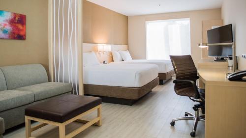 a hotel room with two beds and a couch and a desk at Hyatt Place Managua in Managua
