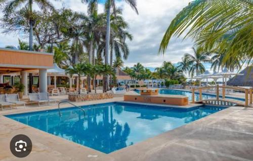 a swimming pool at a resort with palm trees at Casa con vista a la Marina, A UNOS PASOS DE LA PLAYA in Puerto Aventuras