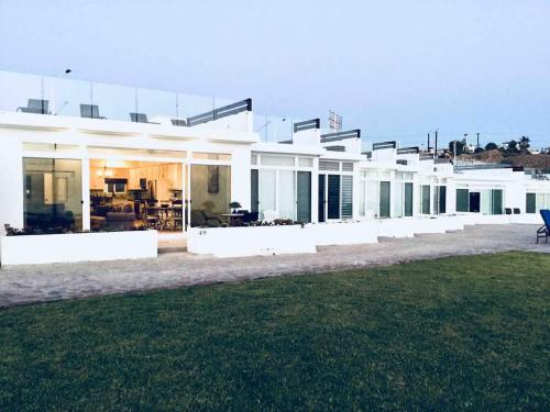a large white house with a lawn in front of it at Beachfront Boutique Villa Cazadores in Rosarito