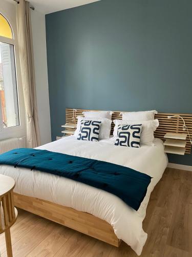 une chambre avec un grand lit aux murs bleus dans l'établissement charmant 2 pièces, à Cormeilles-en-Parisis