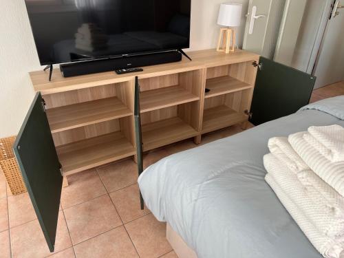 a television on a wooden stand with a bed at Central Menton Beach Retreat in Menton