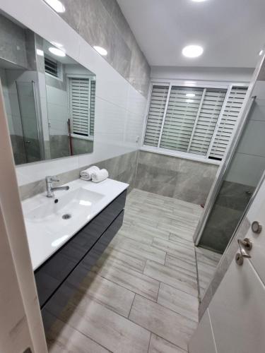 a white bathroom with a sink and a shower at kikar natanya in Netanya
