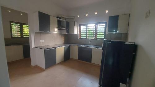 a large kitchen with black and white cabinets and windows at Orange valley Residency Thodupuzha in Thodupuzha
