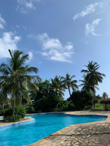 a swimming pool with palm trees in the background at Sophlin home in Ukunda