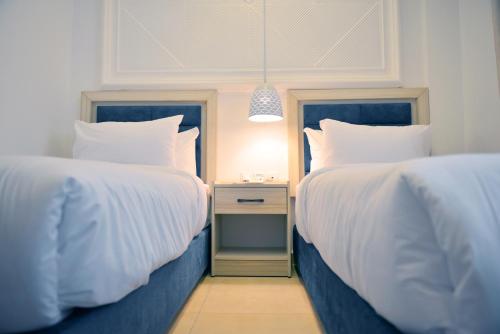 two beds with white sheets and a night stand in a bedroom at Petra Karam Hotel in Wadi Musa
