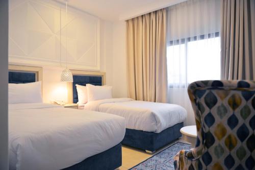 a hotel room with two beds and a chair at Petra Karam Hotel in Wadi Musa